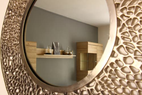 Decorative round mirror with textured frame reflecting modern bathroom vanity in Le Cardinal apartment, Reims hotel