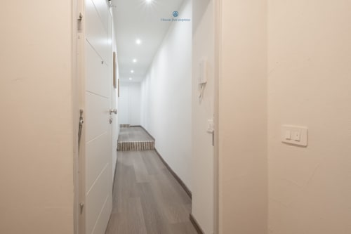 Luminoso e moderno corridoio dell'House Live Express, appartamento a Cagliari con pareti bianche, pavimento in legno scuro e design contemporaneo