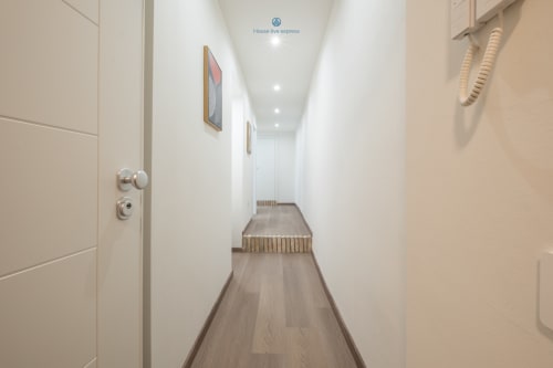 Corridoio moderno e luminoso dell'appartamento House Live Express a Cagliari con pavimentazione in legno e pareti bianche