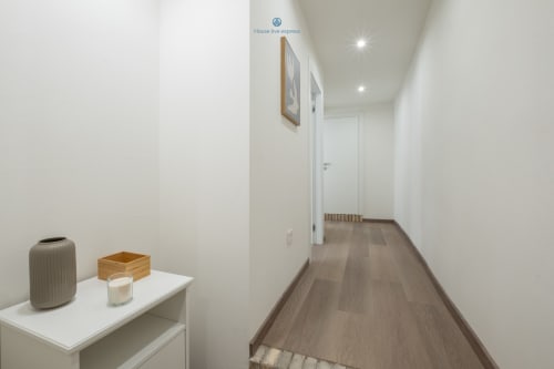 Corridoio moderno dell'appartamento House Live Express a Cagliari con pareti bianche, pavimento in legno e arredamento minimalista