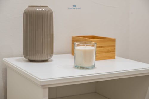 Tavolo bianco con vaso in ceramica rigato, candela in vetro e scatola in legno nell'appartamento Domo de Mesu di House Live Express