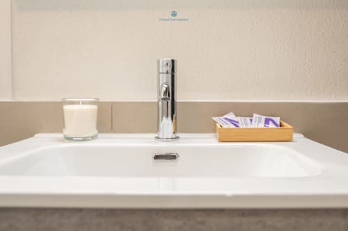 Moderno lavabo del bagno con rubinetto cromato, candela e cestino di cortesia presso House Live Express a Cagliari