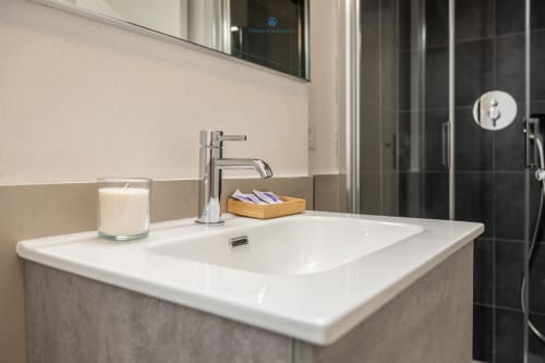 Lavabo moderno con rubinetto cromato, candela e portasapone in legno presso House Live Express a Cagliari