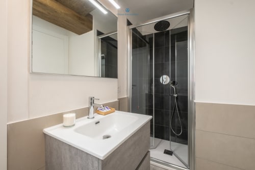 Bagno moderno di House Live Express a Cagliari con lavabo bianco, doccia con piastrelle nere e soffione pioggia rotondo
