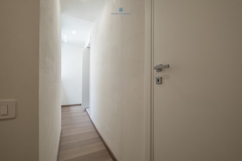 Luminoso corridoio moderno dell'appartamento House Live Express a Cagliari, con pavimenti in legno chiaro e pareti bianche