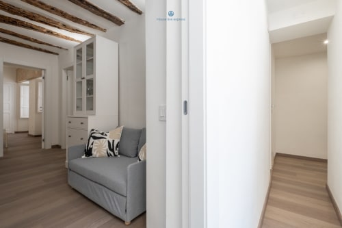 Zona living moderna con divano grigio, mobili bianchi, travi in legno e pavimenti in parquet a House Live Express