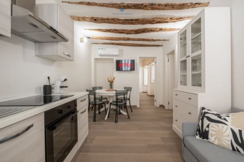 Cucina e zona living di moderno appartamento con travi in legno a vista presso House Live Express a Cagliari