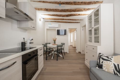 Zona cucina-sala da pranzo moderna nell'appartamento House Live Express a Cagliari, con mobili bianchi, travi in legno rustico
