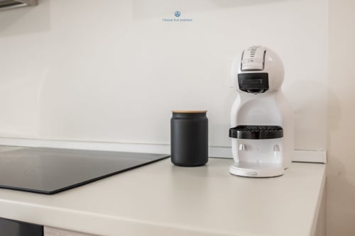 Macchina espresso bianca e contenitore caffè nero sulla scrivania bianca dell'appartamento House Live Express a Cagliari