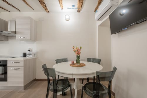 Zona cucina-soggiorno moderna nell'appartamento House Live Express a Cagliari, con tavolo rotondo bianco, sedie scure e completamente attrezzata
