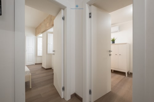Corridoio moderno dell'appartamento presso House Live Express Cagliari con porte bianche, pavimenti in legno e interno minimalista luminoso