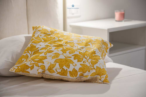 Cuscino con motivo floreale giallo su letto bianco in camera dell'appartamento House Live Express con comodino moderno e arredamento contemporaneo
