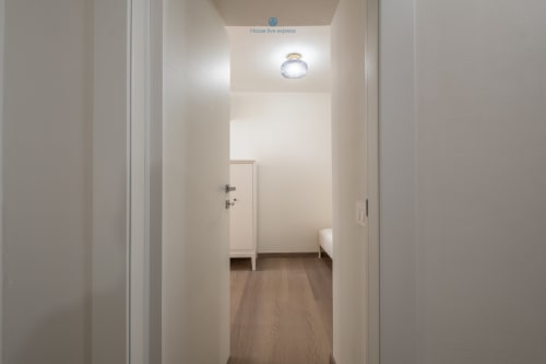 Luminoso corridoio dell'appartamento House Live Express a Cagliari, con pavimenti in legno e moderni elementi di illuminazione che conducono al soggiorno