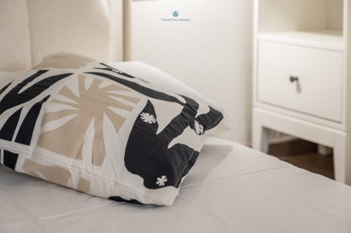 Cuscino decorativo a motivi geometrici bianco e nero sul letto dell'appartamento House Live Express a Cagliari