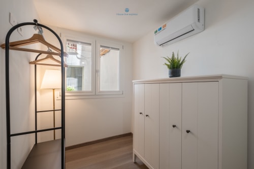 Camera moderna di House Live Express a Cagliari con armadio, aria condizionata, appendiabiti in legno e pianta in vaso