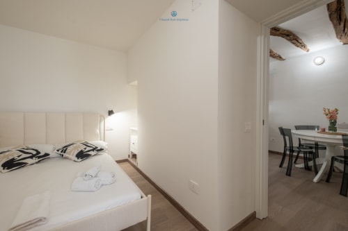 Camera da letto moderna e luminosa con letto a testiera bianca presso l'appartamento House Live Express Cagliari, che si apre sulla zona living
