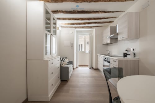 Moderna cucina a galera nell'appartamento House Live Express a Cagliari con cabinetry bianca, travi in legno a vista e open space