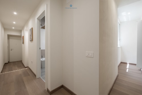 Corridoio moderno dell'appartamento House Live Express a Cagliari, con pareti bianche, pavimento in legno e porte aperte