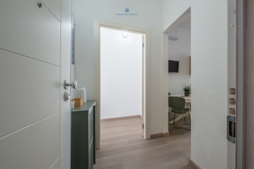 Ingresso moderno dell'appartamento di House Live Express Cagliari con porte bianche, pavimenti in legno e mobili con accenti verdi