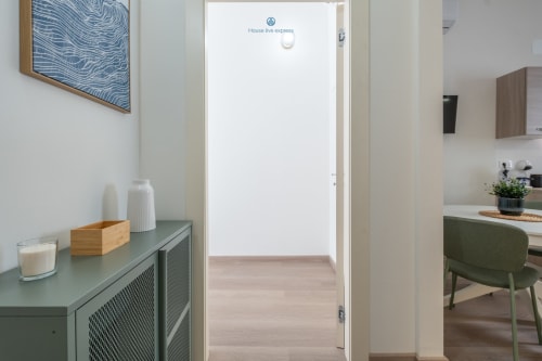 Corridoio moderno dell'appartamento presso House Live Express a Cagliari con consolle verde e porta aperta verso la zona soggiorno