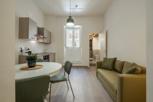 Moderno appartamento a House Live Express a Cagliari con cucina a vista, zona pranzo, divano e porta con vista sulla città