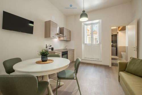 Moderno spazio living con tavolo da pranzo, cucina, TV e vista sulla città presso House Live Express a Cagliari