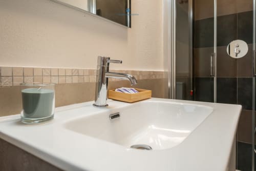 Moderno bagno con lavabo bianco, rubinetto cromato e accessori nell'appartamento House Live Express a Cagliari