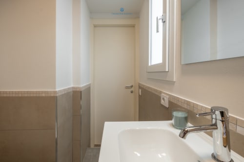 Bagno moderno nell'appartamento House Live Express a Cagliari, con lavabo bianco, rubinetto cromato, piastrelle beige e porta verso il corridoio.