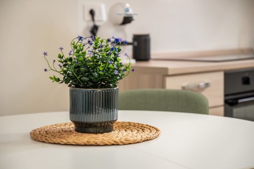 Fiori viola in vaso ceramico a trama rigata su tovaglietta intrecciata al tavolo da pranzo dell'appartamento House Live Express Cagliari