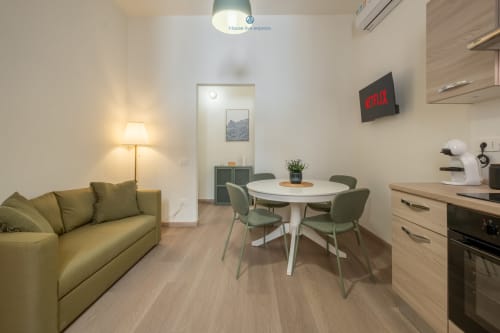 Moderno appartamento a Cagliari con divano verde oliva, tavolo rotondo, angolo cottura e TV Netflix presso House Live Express