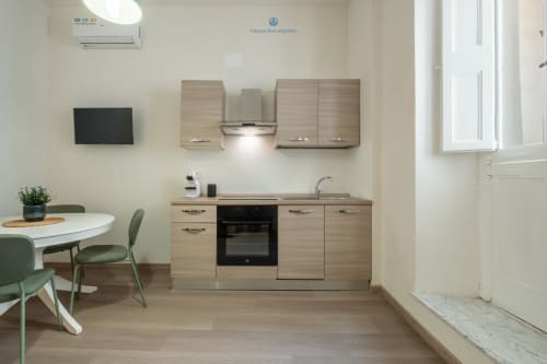 Cucina moderna con mobili in legno, forno nero e zona pranzo presso House Live Express a Cagliari