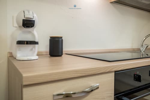 Piano cucina di House Live Express Cagliari con macchina da caffè, barattolo nero e top in legno