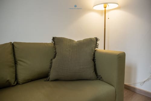 Divano verde oliva con cuscini decorativi e lampada da terra in ottone nell'appartamento House Live Express a Cagliari
