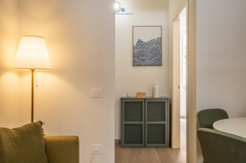 Moderno salotto dell'appartamento a House Live Express a Cagliari con mobile verde, opere d'arte, lampada e vista sulla città