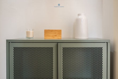 Elegante mobile verde con ante a rete nell'appartamento House Live Express, decorato con candela, blocco di legno e vaso bianco