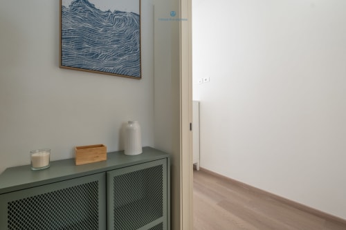 Ingresso moderno dell'appartamento House Live Express Cagliari con mobile verde, vaso bianco e arte murale costiera