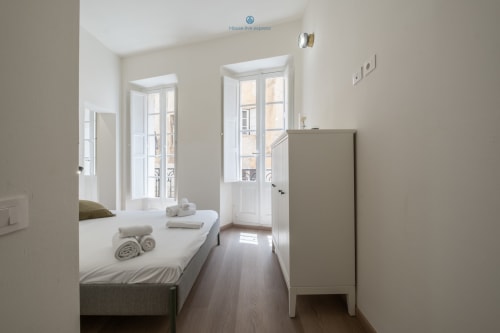 Camera moderna di House Live Express a Cagliari con letto singolo, pavimenti in legno, porte-finestre e vista sulla città