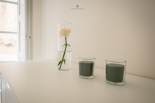 Arredamento minimalista presso House Live Express: un alto vaso con fiore crema, candele verdi su superficie bianca accanto alla finestra