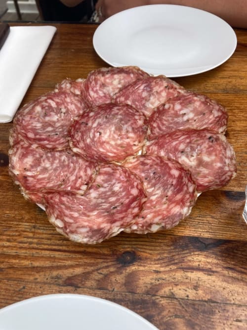 Sliced salami charcuterie board on wooden table at Agriturismo Colle Mura, Gualdo Tadino