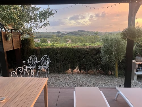 Sunset terrace at B&B Wine And Cooking Penedès with decorative chairs overlooking vineyards in El Pla Del Penedès, Barcelona