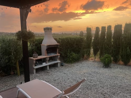 Outdoor patio at sunset with wood-fired grill overlooking vineyard rows at Penedès wine country near Barcelona