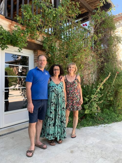 Trois clients souriants devant l'entrée couverte de lierre du Gîte Le Pignié à Lescure-d'Albigeois