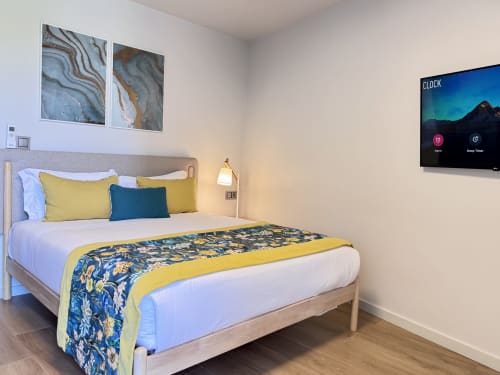 Chambre moderne au RIA CENTRUM Smart Residence à Aveiro avec lit queen, accents jaunes et bleus, décoration murale et écran plat