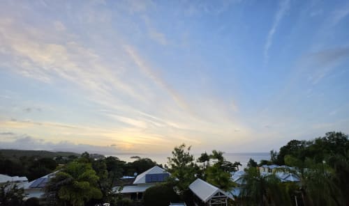 Vue du coucher de soleil sur l'océan depuis le balcon de la Suite Azur à Clémara Evasion, Schœlcher, Martinique avec végétation tropicale