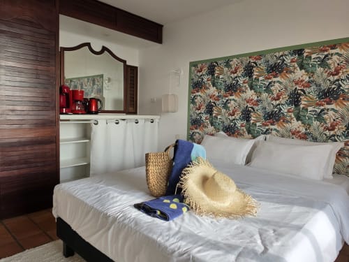 Chambre Suite Azur à Clémara Evasion avec tête de lit tropicale fleurie, draps blancs et accessoires de plage à Schœlcher