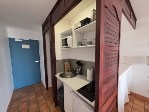Petite kitchenette dans la Suite Azur de Clémara Evasion, Schœlcher avec cuisinière, évier et rangements blancs
