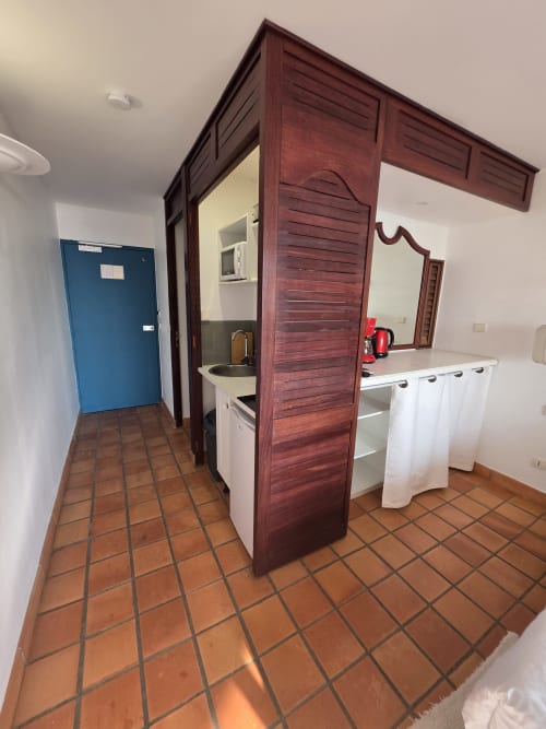 Kitchenette Suite Azur avec carrelage en terre cuite, mobilier en bois foncé, évier et équipements blancs à Clémara Evasion, Martinique