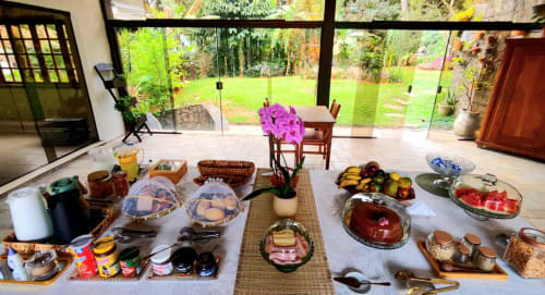Buffet de café da manhã na Casa do Sol Ilhabela com vista para o jardim através de janelas do piso ao teto