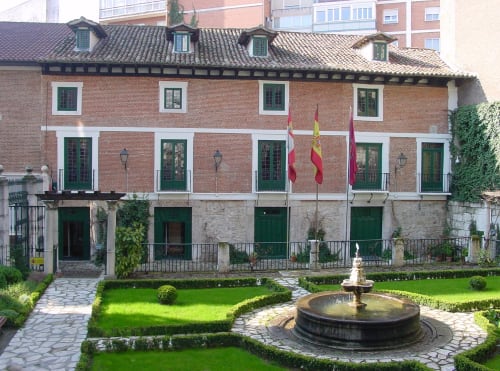 Patio del Palacio Mambrilla en Valladolid: fachada de ladrillo, fuente y jardines bien cuidados