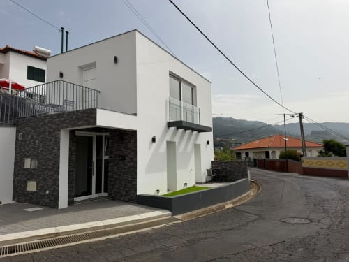 Vila Moderna Sunshine 85 em Ribeira Brava, Madeira com fachada em pedra branca e escura, pátio privativo e vista de montanha